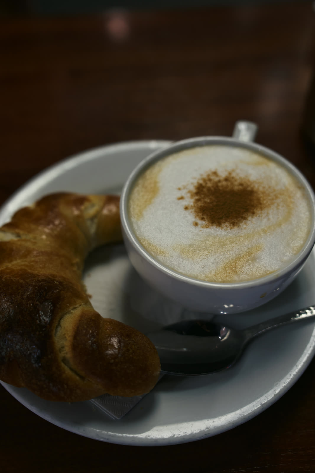 Cappuccino with cinnamon next to a croissant